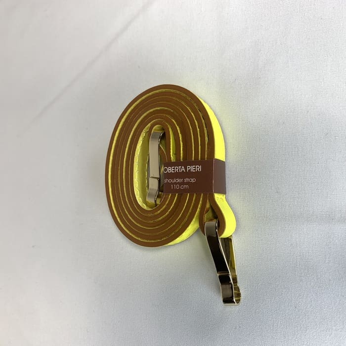 The yellow shoulder strap with gold fittings is coiled and the brown "ROBERTA PIERI shoulder strap 110 cm" label is adorned on the white surface.