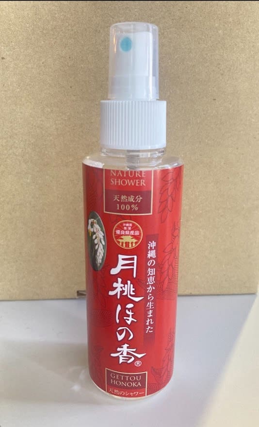 A red spray bottle with the words "Nature Shower" written on a beige background. White spray nozzle and cap.
