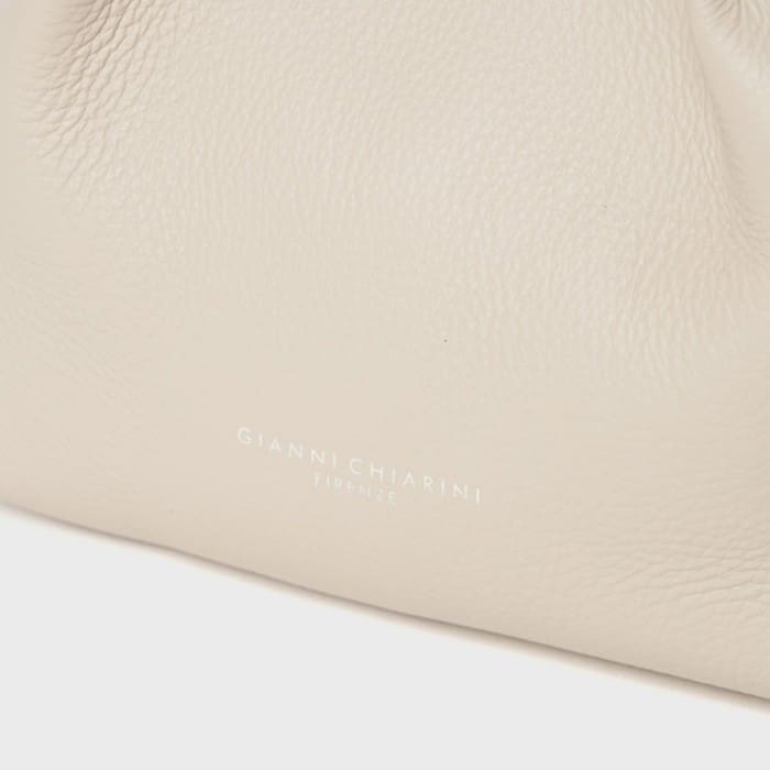 A close-up of the textured light beige leather surface showcasing the refined craftsmanship of the Italian Giannicchiarini. Near the center of the bottom, there is a small white letter embossed with the words "GIANNI CHIARINI FIRENZE".