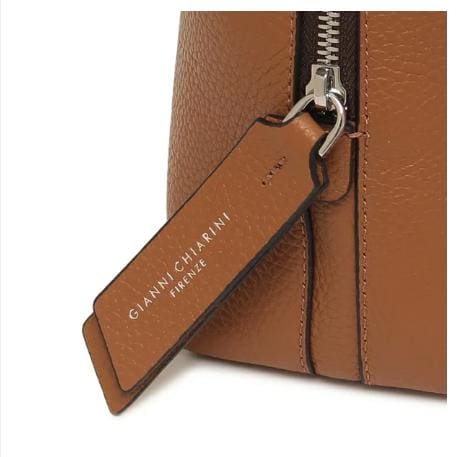 Close-up of GIANNI CHIARINI's brown leather bag. It has a metal zipper and a leather tag that reads "GIANNI CHIARINI FIRENZE" in white. It is made in Italy and exudes timeless Italian elegance.